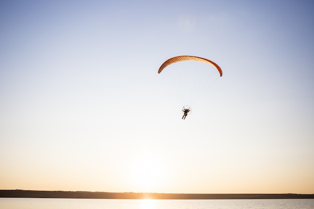 Parapente voando ao pôr do sol