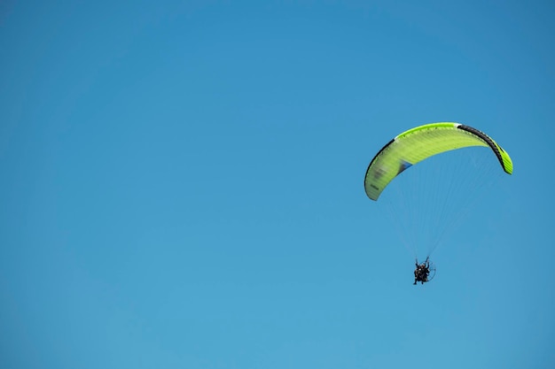 Parapente volando en un día soleado con cielo azul