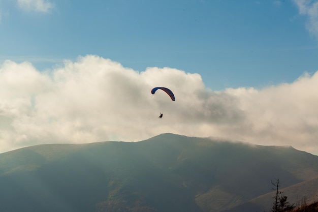 Parapente volando sobre las nubes en el día de verano