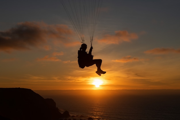 Parapente volando sobre la orilla de estas al atardecer. Deporte de parapente