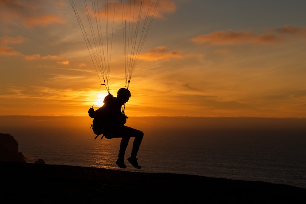 Parapente volando sobre la orilla de estas al atardecer. Deporte de parapente