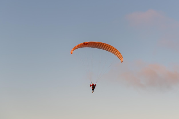 Parapente volando sobre la orilla del mar al atardecer Concepto deportivo de parapente