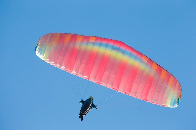 Un parapente vuela en el cielo bajo un parapente multicolor