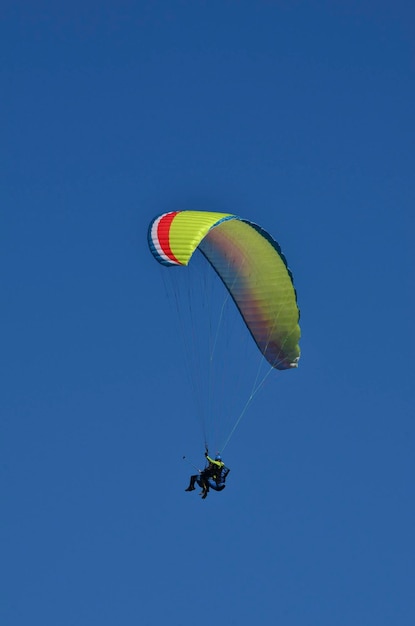 Foto parapenteando sozinho no céu azul sem nuvens.