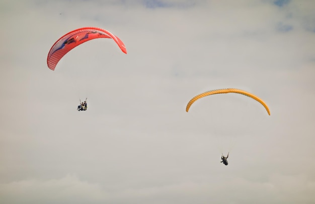 Parapentes coloridos voando juntos no céu nublado