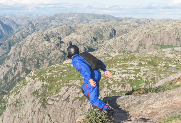 Paraquedista masculino salta de um penhasco sobre um fiorde na Noruega