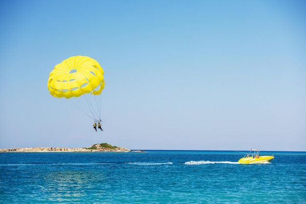 Parasailing über dem Ozean Gelber Parasail-Flügel, der von einem Boot gezogen wird Sportliche Aktivität am Strand