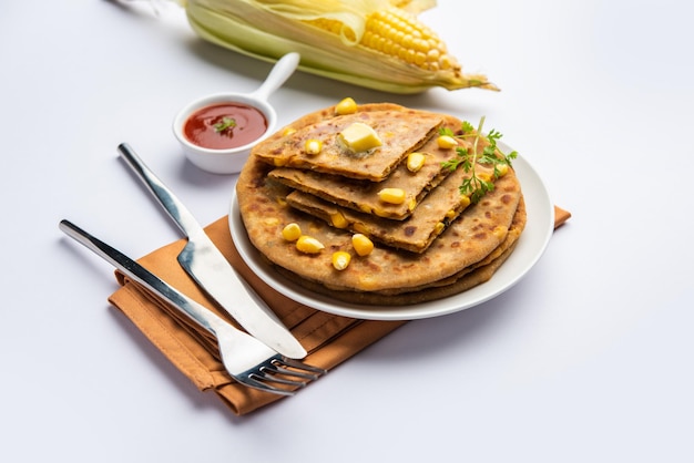 Paratha o parotha rellenos de maíz dulce servidos en un plato Receta de pan plano indio hecho relleno makai