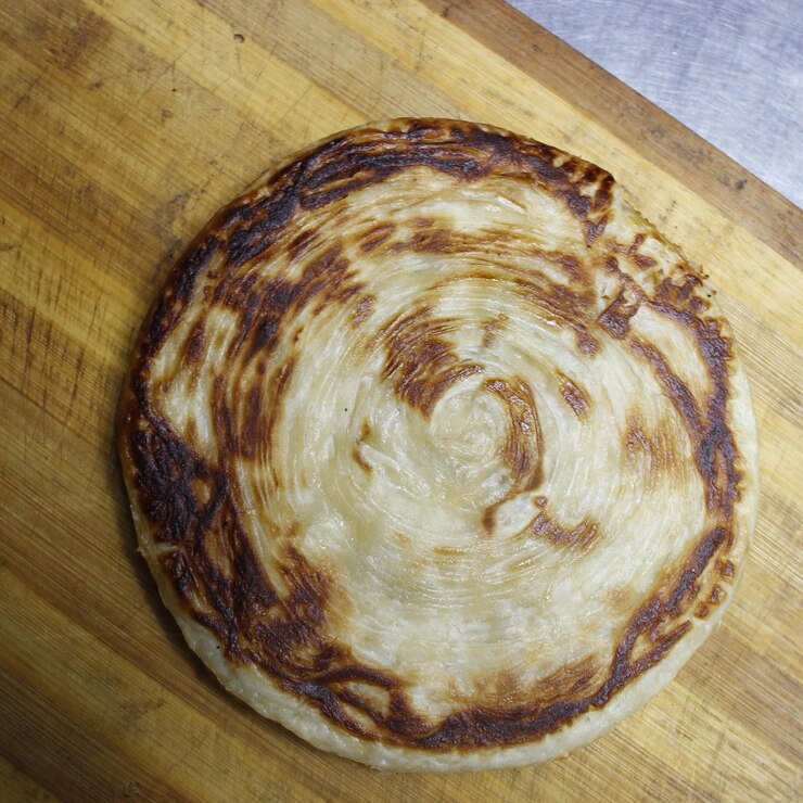 Paratha Pizza Naan Baked Fry está en una superficie de madera