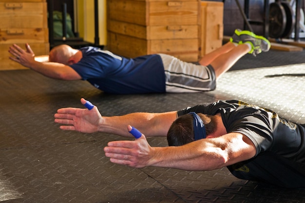 Foto parceiros de fitness fazendo exercícios de super-homem no ginásio