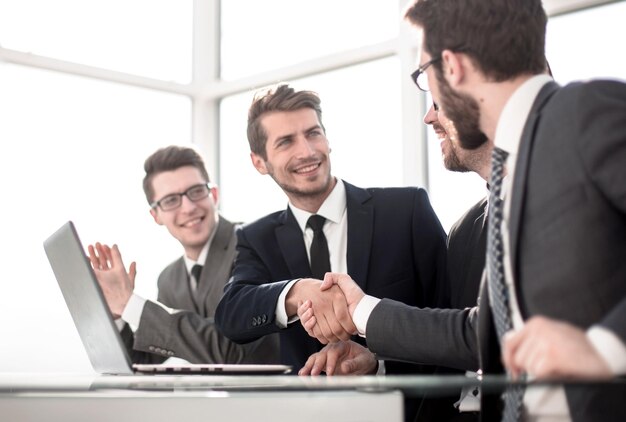 Parceiros de negócios apertando as mãos sentados à mesa do escritório