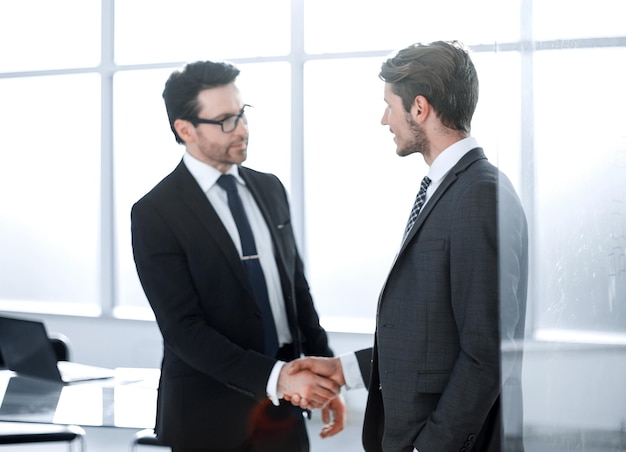 Parceiros de negócios de aperto de mão no fundo do local de trabalho