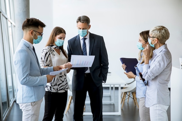 Parceiros de negócios em pé e olhando para os resultados dos negócios no escritório enquanto usam máscaras para proteção contra vírus