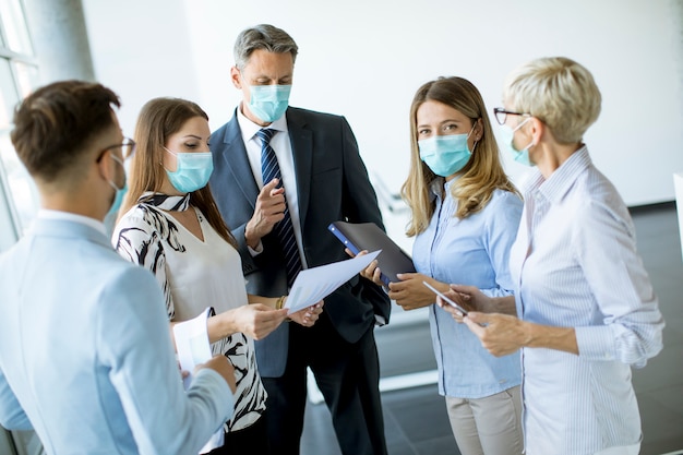 Parceiros de negócios em pé e olhando para os resultados dos negócios no escritório enquanto usam máscaras para proteção contra vírus