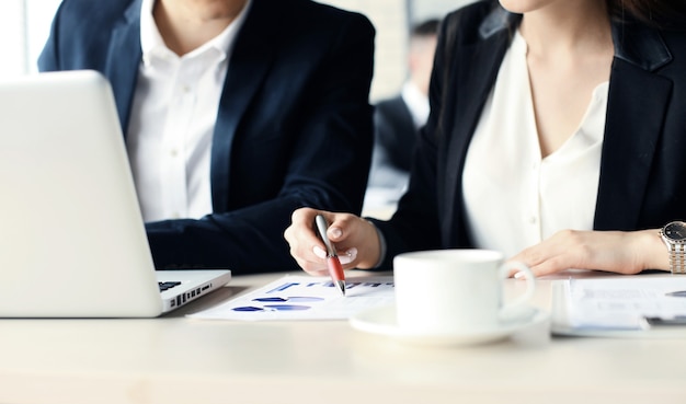 Parceiros de negócios trabalhando juntos na mesa do escritório, eles estão usando um laptop.