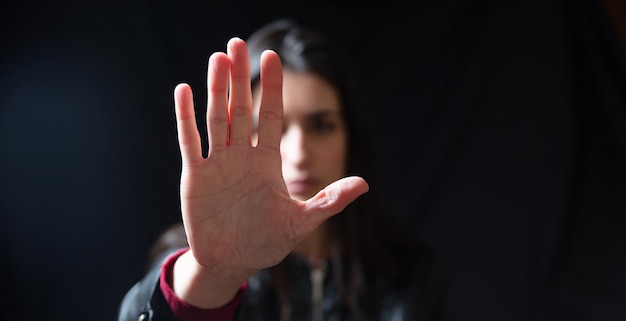 Foto pare a violência contra as mulheres jovem mulher com a mão levantada para dissuadir o espaço de fundo preto