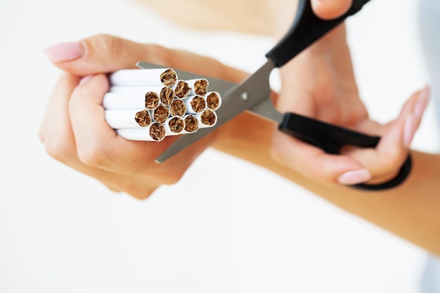 Pare de fumar perto da mulher corta um cigarro com uma tesoura