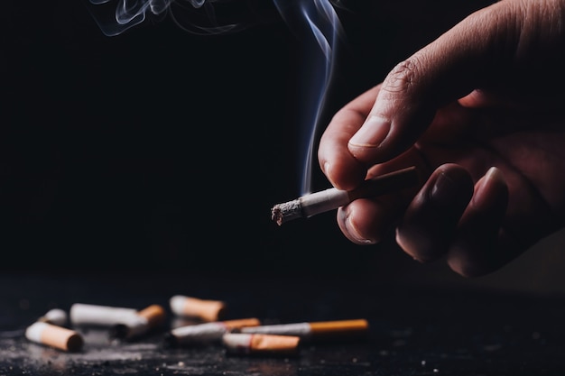Foto pare de fumar .world no tobacco day.close uma mão segurando um cigarro amassado e fumegante com fumaça mão fumar cigarro, estilo de vida saudável