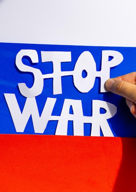 Pare o conflito de guerra entre a Ucrânia e a Rússia Um homem segurando um recorte feito à mão com um slogan não à guerra com a bandeira russa no fundo turva invasão da foto vertical da Ucrânia