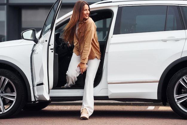 Parece fora do carro Mulher jovem e bonita na moda e seu automóvel moderno