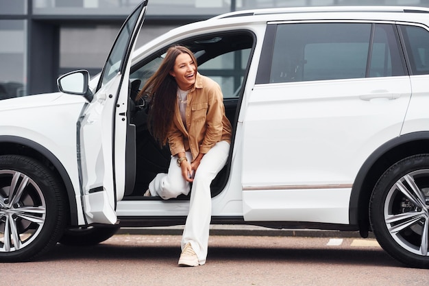 Parece fora do carro Mulher jovem e bonita na moda e seu automóvel moderno