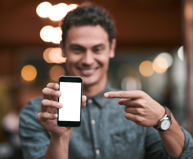 Parece que se están volviendo populares Foto de un joven confiado sosteniendo un teléfono celular frente a la cámara mientras está parado dentro de una cervecería durante el día