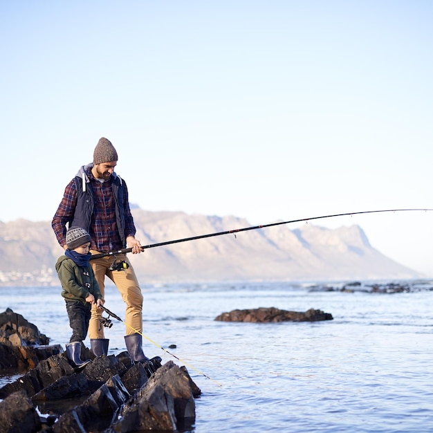 Parece que tienes algo Foto de un lindo niño pescando con su padre junto al mar