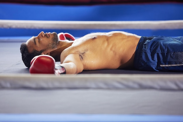 Parece uma foto recortada de um belo jovem boxeador masculino deitado no ringue com os olhos fechados depois de uma luta