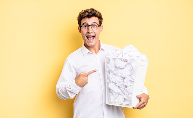 Parecendo animado e surpreso, apontando para o lado e para cima para copiar o espaço. conceito de papel de lixo