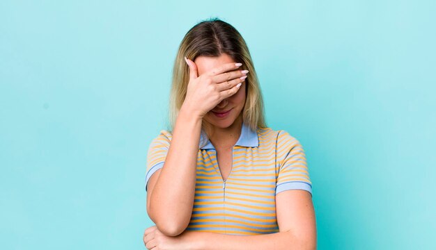 Parecendo estressado envergonhado ou chateado com uma dor de cabeça cobrindo o rosto com a mão