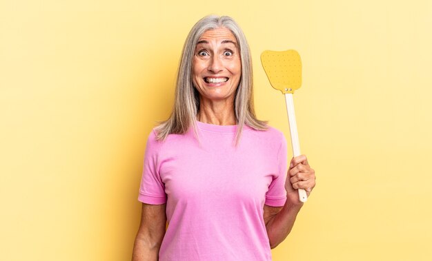 Parecendo feliz e agradavelmente surpreso, animado com uma expressão fascinada e chocada e segurando um mata-moscas