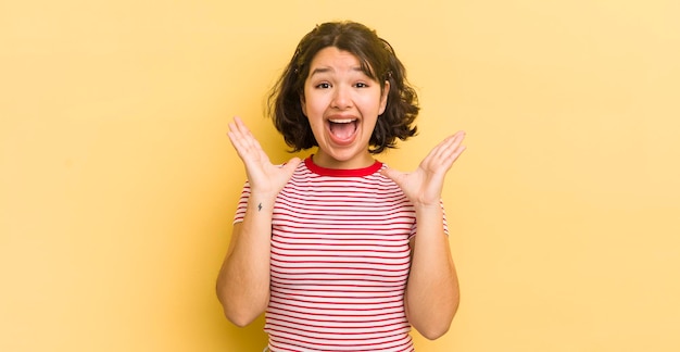 Parecendo feliz e animado chocado com uma surpresa inesperada com as duas mãos abertas ao lado do rosto