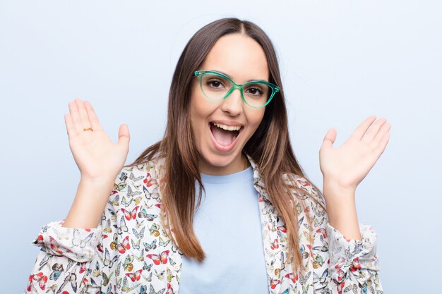 parecendo feliz e animado, chocado com uma surpresa inesperada com as duas mãos abertas ao lado do rosto