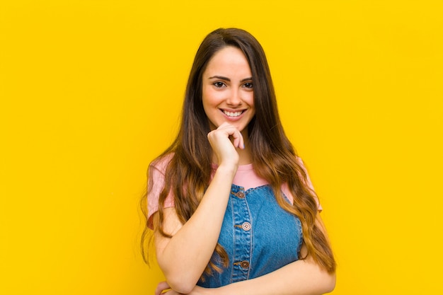 parecendo feliz e sorridente com a mão no queixo, imaginando ou fazendo uma pergunta, comparando opções