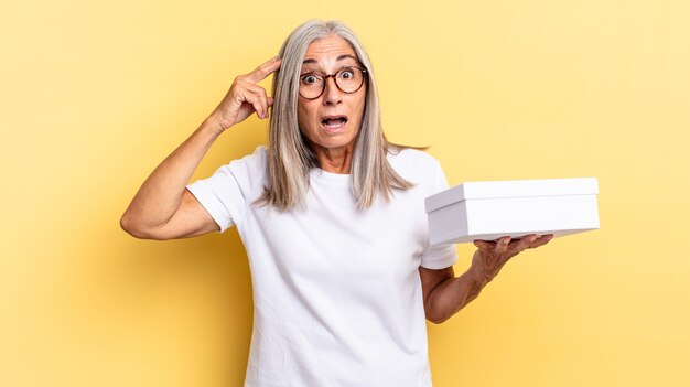 Parecendo feliz, espantado e surpreso, sorrindo e percebendo boas notícias incríveis e incríveis e segurando uma caixa branca