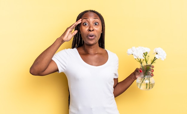 Parecendo feliz, espantado e surpreso, sorrindo e percebendo uma boa notícia incrível. conceito de flores decorativas