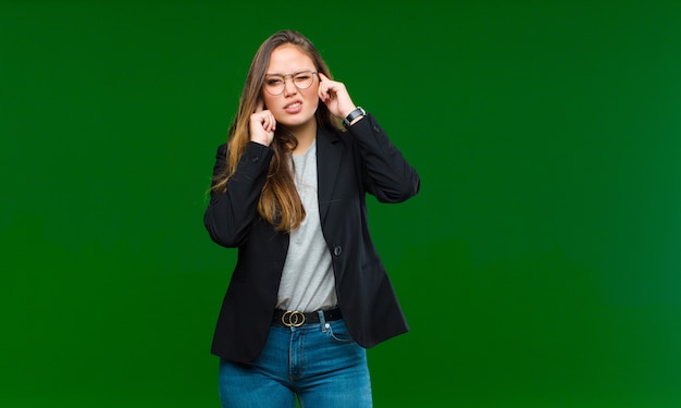 parecendo irritado, estressado e irritado, cobrindo ambos os ouvidos com um ruído ensurdecedor, som ou música alta