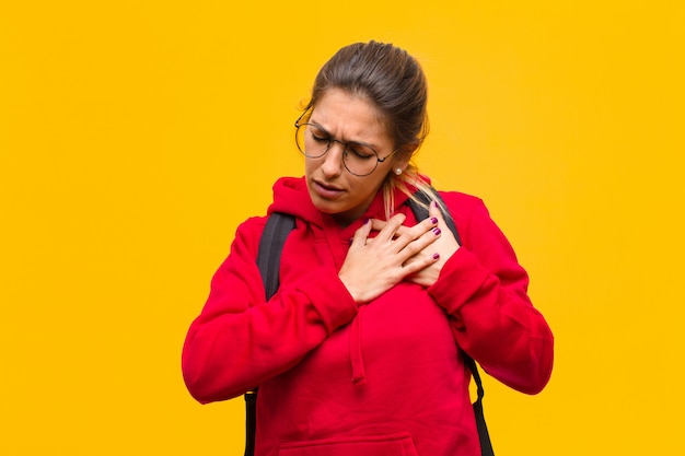 Parecendo triste, magoado e com o coração partido, segurando as duas mãos perto do coração, chorando e sentindo-se deprimido