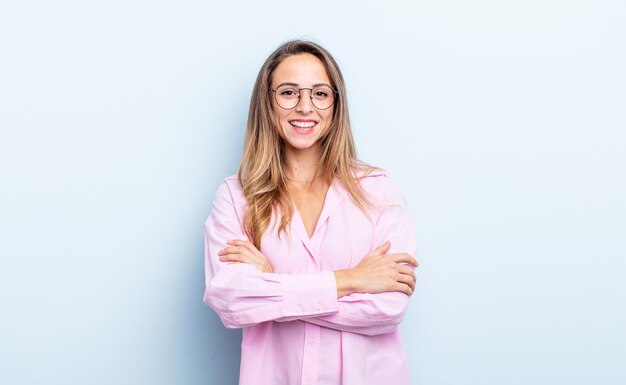 Pareciendo un triunfador feliz, orgulloso y satisfecho sonriendo con los brazos cruzados