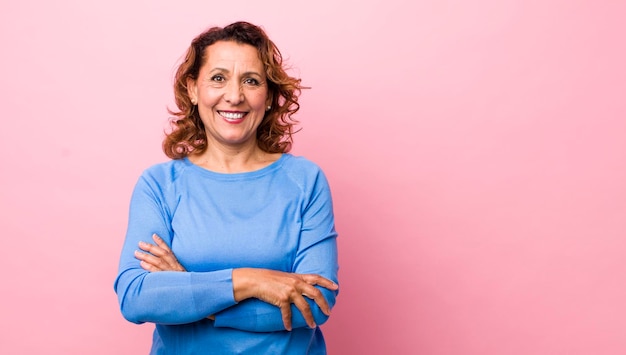 Pareciendo un triunfador feliz, orgulloso y satisfecho sonriendo con los brazos cruzados