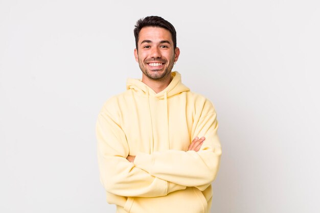 Pareciendo un triunfador feliz, orgulloso y satisfecho sonriendo con los brazos cruzados