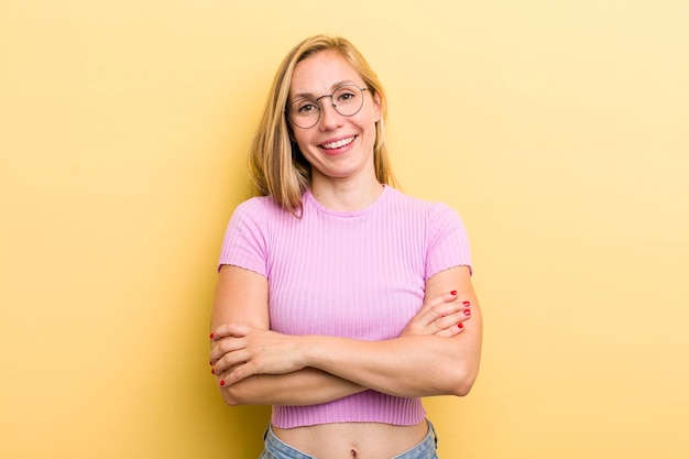 Pareciendo un triunfador feliz, orgulloso y satisfecho sonriendo con los brazos cruzados