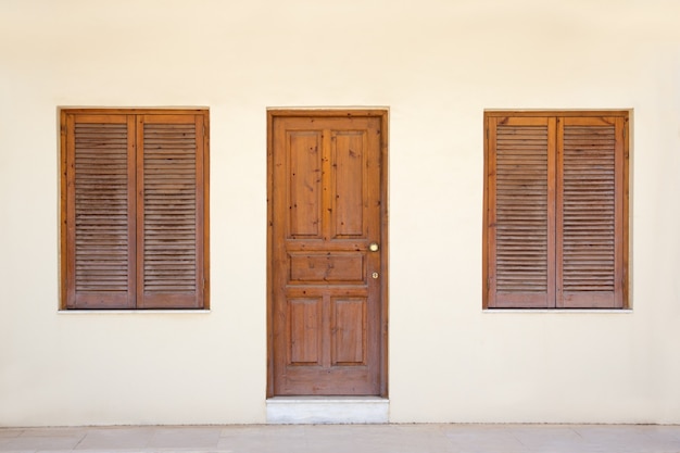 Pared amarilla con puerta retro y dos ventanas.