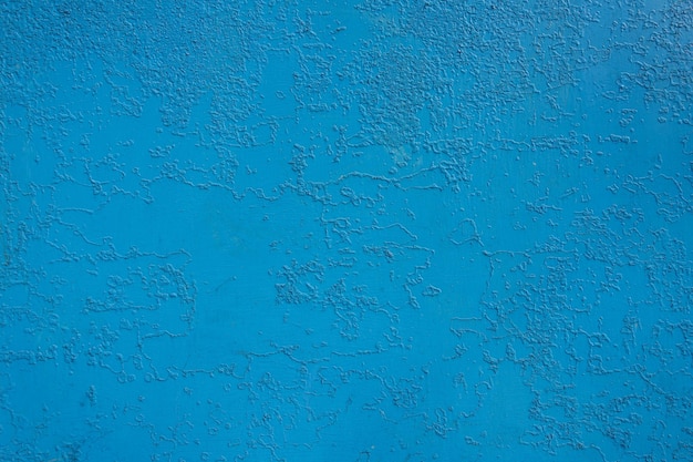 pared de una antigua casa de pueblo pintada con pintura azul, que se agrietó con el tiempo debido al mal tiempo