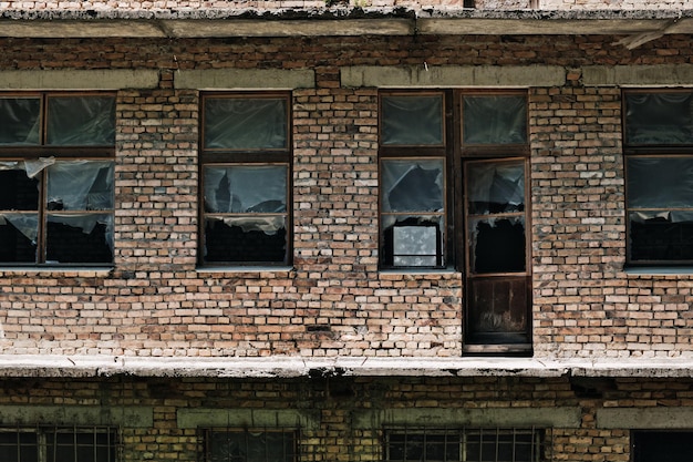 La pared de un antiguo edificio de ladrillo abandonado con ventanas rotas