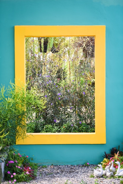 Pared azul con cuadrado amarillo con plantas ornamentales, decoración de jardines y flores.