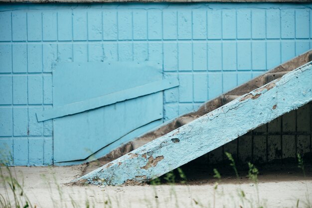 Pared azul del edificio con trampilla y escalera