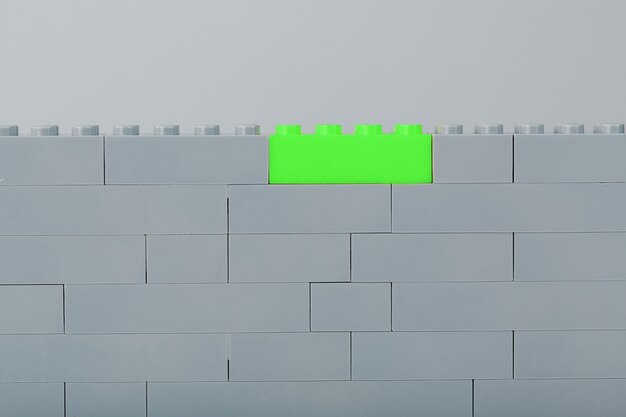Una pared hecha de piezas de kit de construcción para niños con ladrillos de color verde brillante.