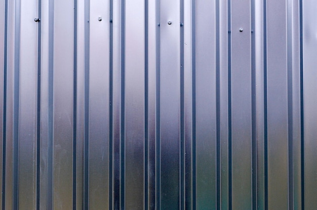Pared de hierro de estaño plateado con rayas verticales y diagonales de un perfil metálico de una lámina de metal