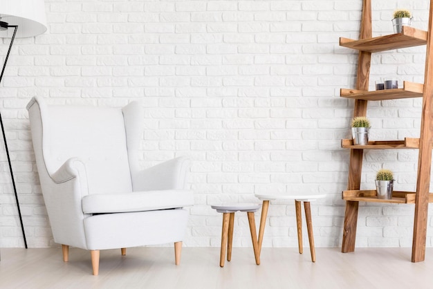 Una pared de ladrillo blanco con una silla blanca y un estante de madera con plantas.